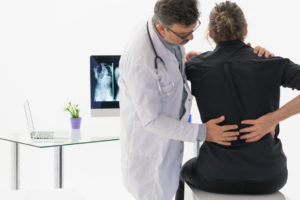 Doctor examining a woman's lower back pain