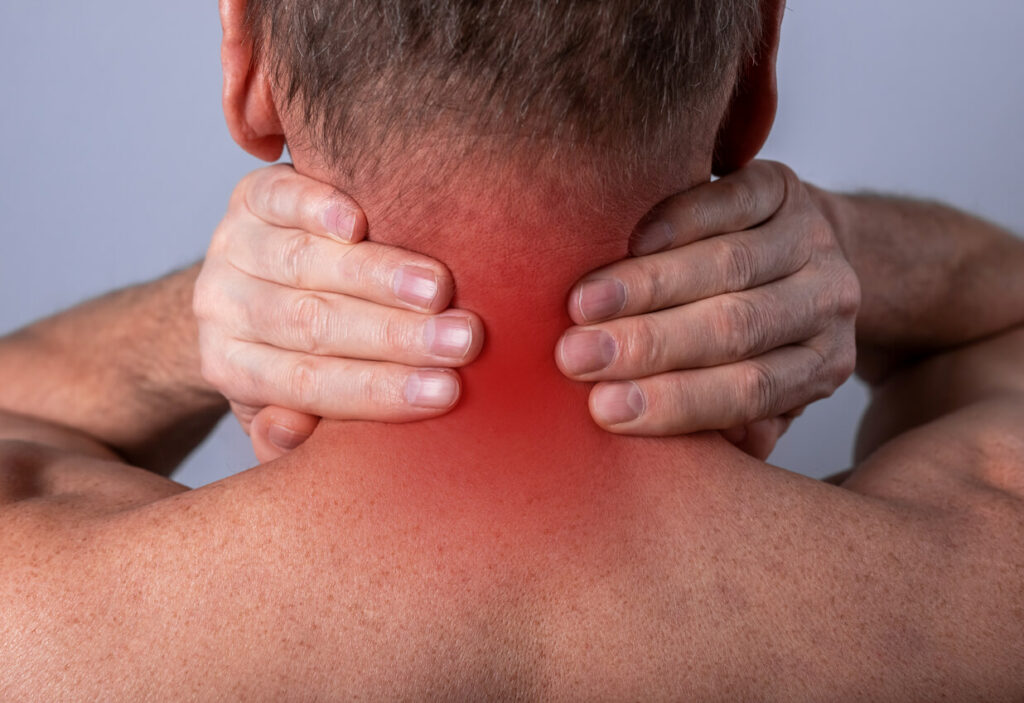 A man's hands hold his neck due to severe neck pain caused by whiplash.